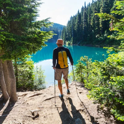 Photo d'un randonneur devant un lac bordé d'arbres, illustrant les voyages au Canada en été