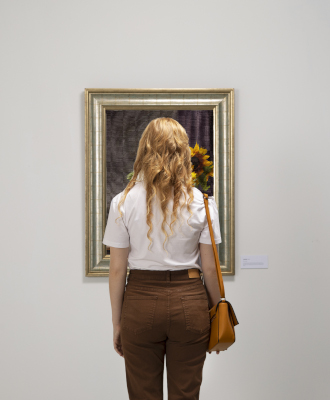 Photo d'une femme de dos, admirant un tableau dans un musée dans le cadre d'un voyage culturel