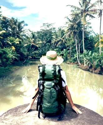 Voyageur de dos, muni de son sac à dos, observant une rivière sauvage